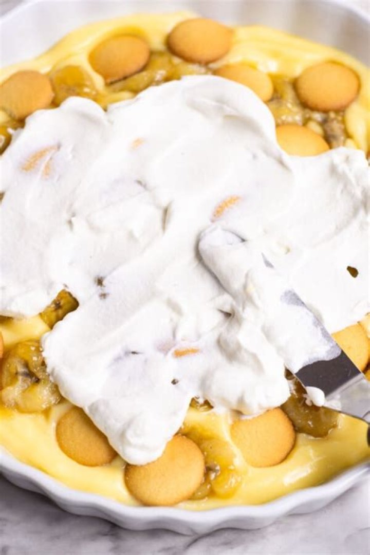 Spreading pudding over layers of banana and cookies.